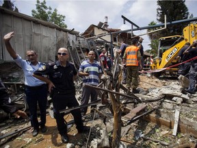 Israeli police officers secure a destroyed house that was hit by a rocket fired by Palestinian militants from Gaza, in Yahud, a Tel Aviv suburb near the airport, central Israel. On Thursday, July 31, 2014, the U.N.'s top human rights official accused both Israel and Hamas of committing war crimes in the Gaza fighting.