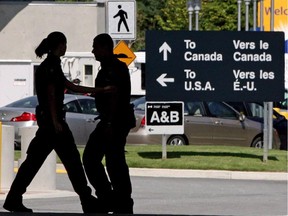 Canadian border guards are silhouetted as they replace each other at an inspection booth in Surrey, B.C., in 2009.
