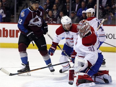 Montreal Canadiens goalie Carey Price, front, makes a pad save on a shot off the stick of Colorado Avalanche right wing Jarome Iginla, left, as Canadiens defenceman Tom Gilbert, centre, looks on in the first period of an NHL hockey game in Denver on Monday, Dec. 1, 2014.