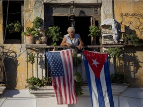 Javier Yanez stands on his balcony where he hung a U.S. and Cuban flag in Old Havana Cuba, Friday, Dec. 19, 2014. After the surprise announcement on Wednesday of the restoration of diplomatic ties between Cuba and the U.S., many Cubans expressed hope that it will mean greater access to jobs and the comforts taken for granted elsewhere, and lift their struggling economy. However others feared a cultural onslaught, or that crime and drugs, both rare in Cuba, will become common along with visitors from the United States.
