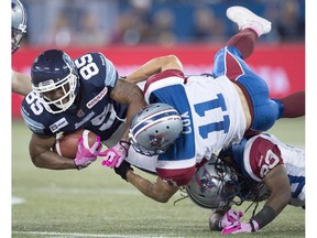 Toronto Argonauts wide receiver John Chiles (85) is tackled by Montreal Alouettes linebacker Chip Cox (11) and defensive back Jerald Brown (bottom) during second half CFL action in Toronto on Saturday October 18, 2014.