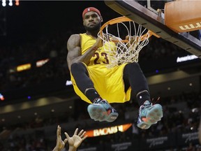 Cleveland Cavaliers forward LeBron James  hangs onto the basket after a dunk during game against the Miami Heat on Dec. 25, 2014.