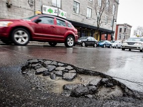 Cars drive past a large pothole on St-Laurent Blvd. near the corner of Sherbrooke St. in Montreal on Monday, Feb. 25, 2013.