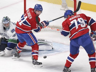 Montreal Canadiens Andrei Markov and Brendan Gallagher try to control loose puck in front of Vancouver Canucks goalie Ryan Miller during second period of National Hockey League game in Montreal Tuesday December 09, 2014.