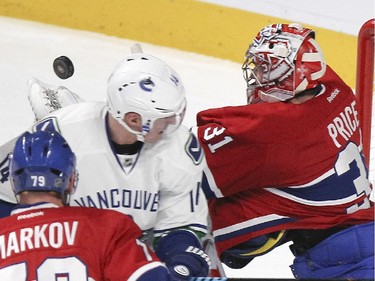 Montreal Canadiens goalie Carey Price reaches for puck behind Vancouver Canucks Alexandre Burrows as defenceman Andrei Markov defends during National Hockey League game in Montreal Tuesday December 09, 2014.