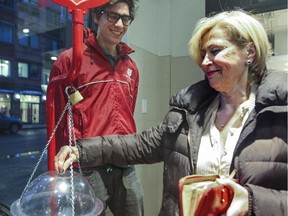 UQAM student Raphael Cossette greets Rea Tsatsoulis as she puts money in a Salvation Army pot at the Cinq Saisons grocery store in Westmount, in Montreal Thursday December 18, 2014.