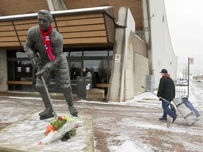 A hockey player walks past a statue honouring late Canadiens captain Jean Béliveau outside the Colisée Jean Béliveau in Longueuil, south of Montreal, on Dec. 3, 2014, the day after Béliveau died at age 83.