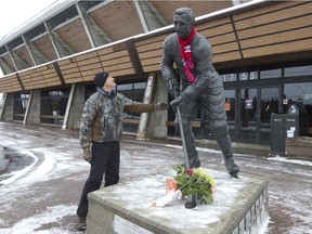 Richard Gauthier places his hand on a statue of late Canadiens captain Jean Béliveau, outside the Colisée Jean Béliveau in Longueuil Dec. 3, 2014. Béliveau died the night before.