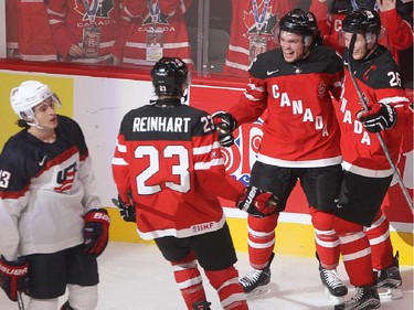 Max Domi, centre, of Team Canada celebrates his goal with teammates Sam Reinhart, left, and Curtis Lazar, right, while Team USA player Sonny Milano stakes by, during third period preliminary round hockey action at the IIHF World Junior Championship in Montreal on Wednesday December 31, 2014.