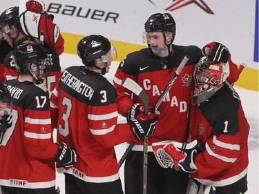 Team Canada goalie Eric Comrie is congratulated by his teammates following win against Team USA in  preliminary round at the World Junior Hockey Championship at the Bell Centre.