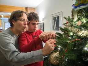Eric Houde, left, and his son Benjamin Cukier-Houde decorate their Christmas tree at their home in Montreal.