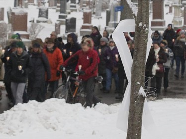Marchers walk by a white ribbon in Notre-Dame-des-Neiges Cemetery in Montreal, Saturday December 6, 2014.  It was part of a day of commemorations to mark the 25th anniversary of the murder of 14 women at the École Polytechnique, by Marc Lépine.  The white ribbon is a symbol of remeberance of the massacre.