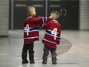 Brothers Peyton Bourré, 5, left, and his brother Emrick, 3, wearing Jean Béliveau No. 4 jerseys, play while waiting with their parents to sign books of condolences for the Canadiens legend who died at age 83 during visitation at the Bell Centre on Dec. 7, 2014.