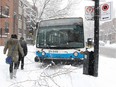 Pedestrians make their way around an STM bus on the sidewalk during a snowstorm in March 2013.