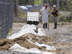 Workrs next to a mound of dirt at Reliance Power Equipment Ltd. in Pointe Claire in May 2014, during soil decontamination operations.