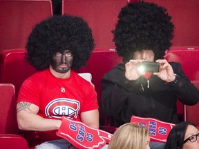 A Montreal Canadiens fan wearing blackface and an afro wig watches the warmup session of the  NHL hockey match between the Montreal Canadiens and the New York Islanders in Montreal on Sunday, November 10, 2013.