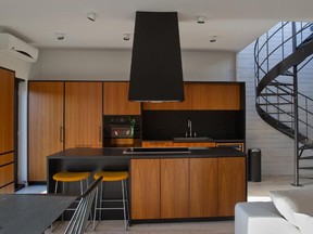 Modern, sleek 'after' of kitchen renovation. The kitchen has been completely transformed, walls removed, an island added, an an adjacent winding staircase leads up to a rooftop patio.