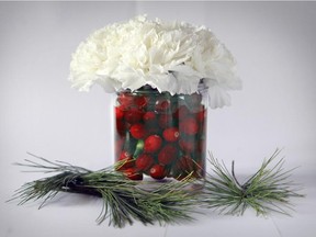 Low-cut and tightly bundled carnations in a jam jar with cranberries.