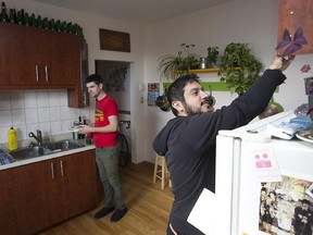 Tending to daily chores, Andres Salas, front, and Chris Erb, in the kitchen of their apartment in Park Extension.