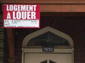 A woman reaches up to remove a for rent sign in Montreal, Tuesday, July 1, 2014, on what's now known as moving day in Quebec.