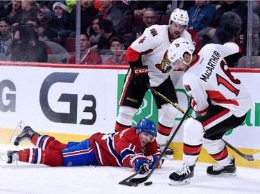 Brendan Gallagher of the Montreal Canadiens fall while skating with the puck in front of Chris Phillips and Clarke MacArthur of the Ottawa Senators during the NHL game at the Bell Centre on December 20, 2014, in Montreal.