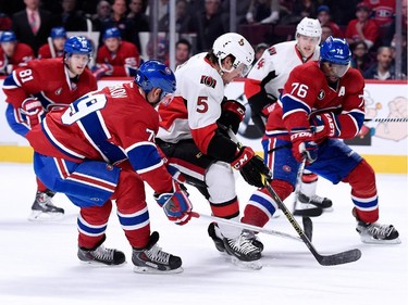 Cody Ceci of the Ottawa Senators attempts to move the puck past P.K. Subban and Andrei Markov of the Montreal Canadiens during the NHL game at the Bell Centre on December 20, 2014, in Montreal.