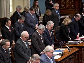 Quebec Premier Philippe Couillard, centre, and members of the National Assembly stand in a minute of silence in memory of the 14 women who died in the Polytechnique tragedy, on Thursday, December 4, 2014 at the legislature in Quebec City.