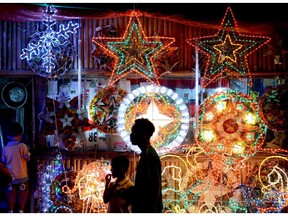Buyers stand in front of lanterns known locally as 'parol' on display along a street in Manila on December 23, 2013. Parol are star-shaped Christmas lanterns patterned to resemble the Star of Bethlehem, and are made from bamboo covered with paper. They are displayed in houses, offices, buildings, and streets, and according to Filipino tradition and beliefs, also represent the victory of light over darkness.