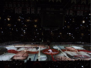 Photographs of Montreal Canadiens legend Jean Beliveau are projected on the ice during a ceremony prior to facing the Vancouver Canucks in NHL hockey action Tuesday, December 9, 2014 in Montreal. Beliveau died last week at the age of 83.