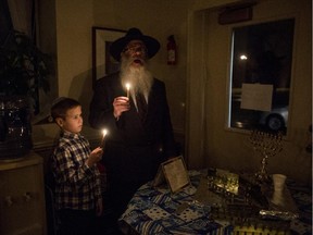 Rabbi Yisroel Weingarten and Aaron Kucherenko, 9, light the first candle on the Menorah on the first night of Hanukkah Tuesday, Dec. 16, 2014 at the Chabad House-Lubavitch of Eastern Michigan in Flint.