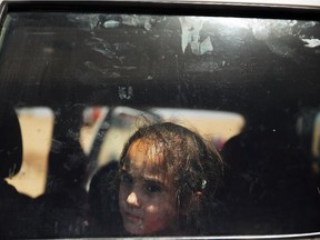 An Iraqi girl look out of a window as over 1,000 Iraqis who have fled fighting in and around the city of Mosul and Tal Afar wait at a Kurdish checkpoint in the hopes of entering a temporary displacement camp on July 1, 2014 in Khazair, Iraq.