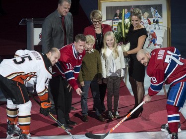 Former Montreal Canadiens captain Saku Koivu, surrounded by family members, drops the puck between Anaheim Ducks' Ryan Getzlaf and Montreal Canadiens' Andrei Markov during a ceremony honouring his career, Thursday, December 18, 2014 in Montreal.