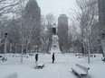 People cross through Dominion Square in downtown Montreal in the midst of a snow storm on Dec. 10, 2014.