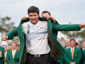 Adam Scott presents Bubba Watson with the green jacket after Watson won the Masters by three strokes at Augusta National Golf Club on April 13, 2014.