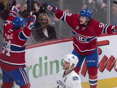 Montreal Canadiens' Tomas Plekanec celebrates his goal with teammate Sven Andrighetto, right, as Vancouver Canucks' Kevin Bieksa skates by during third period NHL hockey action Tuesday, December 9, 2014 in Montreal. The Canadiens beat the Canucks 3-1.
