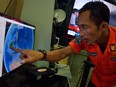 An official from Indonesia's national search and rescue agency in Medan, North Sumatra, points at his computer screen to the position where AirAsia flight QZ8501 went missing off the waters of Indonesia on December 28, 2014. The AirAsia Airbus plane with 162 people on board went missing en route from Indonesia to Singapore early on December 28, officials and the airline said, in the third major incident to affect a Malaysian carrier this year.