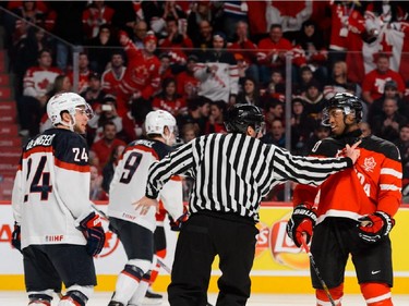 The linesman separates Anthony DeAngelo #24 of Team United States and Anthony Duclair #10 of Team Canada during the 2015 IIHF World Junior Hockey Championship game at the Bell Centre on December 31, 2014 in Montreal, Quebec, Canada.