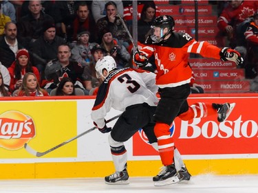 Lawson Crouse #28 of Team Canada jumps beside Ian McCoshen #3 of Team United States during the 2015 IIHF World Junior Hockey Championship game at the Bell Centre on December 31, 2014 in Montreal, Quebec, Canada.