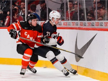 Joe Hicketts #2 of Team Canada pushes Dylan Larkin #21 of Team USA into the boards in a preliminary round game during the 2015 IIHF World Junior Hockey Championships at the Bell Centre on December 31, 2014 in Montreal.