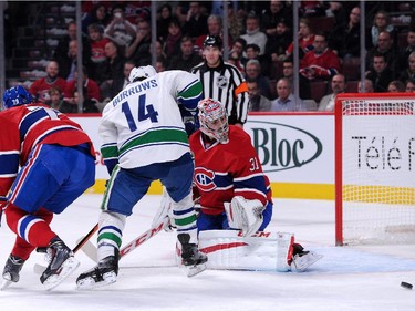 Carey Price of the Montreal Canadiens watches the rebounding puck on an attempt by Alex Burrows (14) of the Vancouver Canucks during the NHL game at the Bell Centre on December 9, 2014 in Montreal, Quebec, Canada.