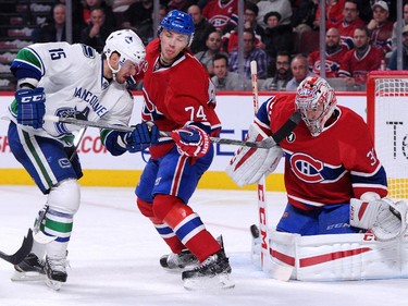Carey Price (#31) of the Montreal Canadiens gets down to stop the incoming puck in front of teammate Alexei Emelin (#74) and Brad Richardson #15 of the Vancouver Canucks during the NHL game at the Bell Centre on December 9, 2014 in Montreal, Quebec, Canada.  The Canadiens defeated the Canucks 3-1.