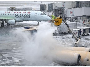 A plane is de-iced during a light snow at LaGuardia Airport in New York, Monday, Jan. 26, 2015. Airlines canceled thousands of flights into and out of East Coast airports as a major snowstorm packing up to three feet of snow barrels down on the region.