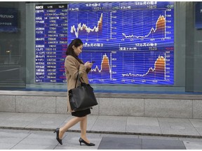 A woman walks by an electronic stock board of a securities firm in Tokyo.