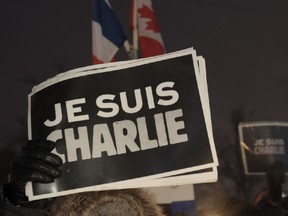 People holds signs reading "I  Am Charlie" during a vigil January 7, 2015 outside  City Hall in Montreal, Canada  for the victims of the shooting at the office of the French satirical magazine Charlie Hebdo.  Twelve people were killed when several gunmen opened fire at Charlie Hebdo's headquarters in Paris, France on January 7th.