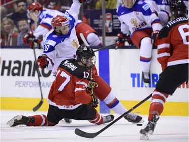 Canada's Connor McDavid slides under Russia's Vladimir Bryukvin during first period gold medal game hockey action at the IIHF World Junior Championship in Toronto on Monday, Jan. 5, 2015.