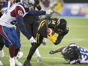Tiger-Cats receiver Terrell Sinkfield stumbles after catching the ball and being hit by Alouettes long-snapper Jerod Zaleski (82) during CFL game in Hamilton on Nov. 8, 2014.