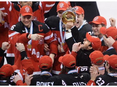Canada's captain Curtis Lazar, left, passes the championship trophy after defeating Russia during third period gold medal hockey action at the IIHF World Junior Championships in Toronto on Monday, January 5, 2015.