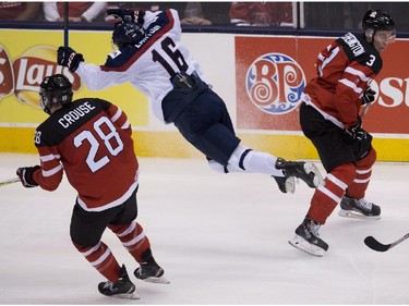 Slovakia forward Robert Lantosi (16) gets tripped up by Canada defenceman Dillon Heatherington (3) during second period semifinal hockey action at the IIHF World Junior Championships in Toronto on Sunday, January 4, 2015.