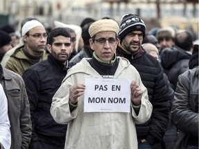 A Muslim man holds a placard, reading "Not in my name", during a gathering on January 9, 2015 near the big mosque of Saint-Etienne, eastern France, after the country's bloodiest attack in half a century on the offices of the weekly satirical Charlie Hebdo killing 12 people on January 7.