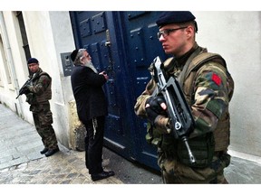 French soldiers secure the access to a Jewish school, in Paris, Tuesday, Jan. 13, 2015. France on Monday ordered 10,000 troops into the streets to protect sensitive sites after three days of bloodshed and terror, amid the hunt for accomplices to the attacks that left 17 people and the three gunmen dead.